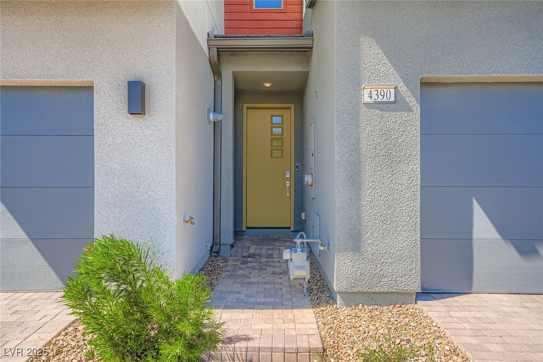 Recessed front entrance with a tan door, paver walkway, gravel landscaping, and address plaque 4390.