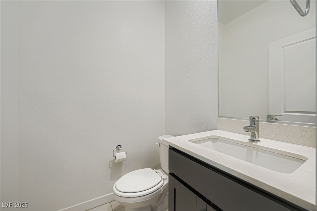 Bathroom with a dark vanity, white sink, large mirror, and toilet.