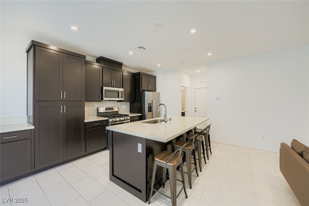 Modern kitchen with dark cabinets, stainless appliances, and a large island with bar seating.