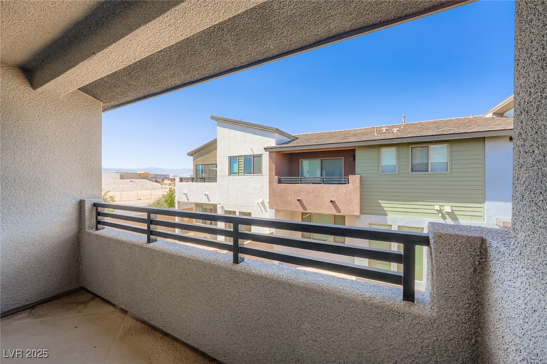 Covered balcony overlooking a neighboring home and distant desert landscape.