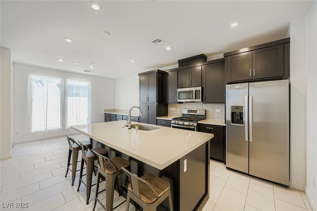 Modern kitchen with a large white island, dark cabinets, and stainless steel appliances.