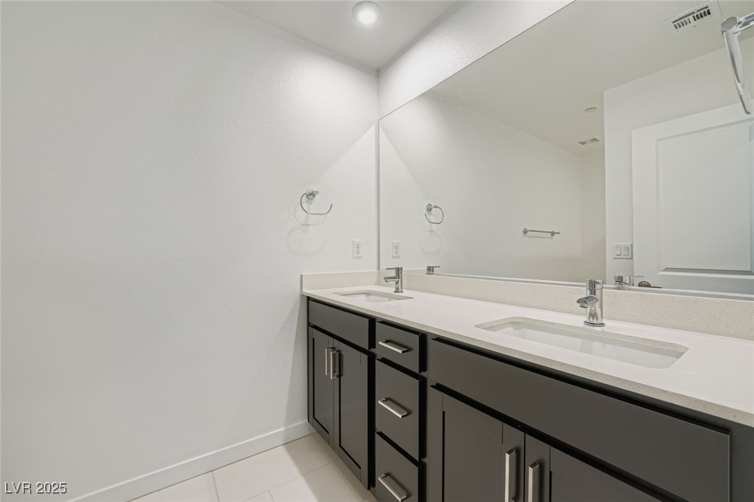 Bathroom vanity with two sinks, dark gray cabinets, and a large mirror.