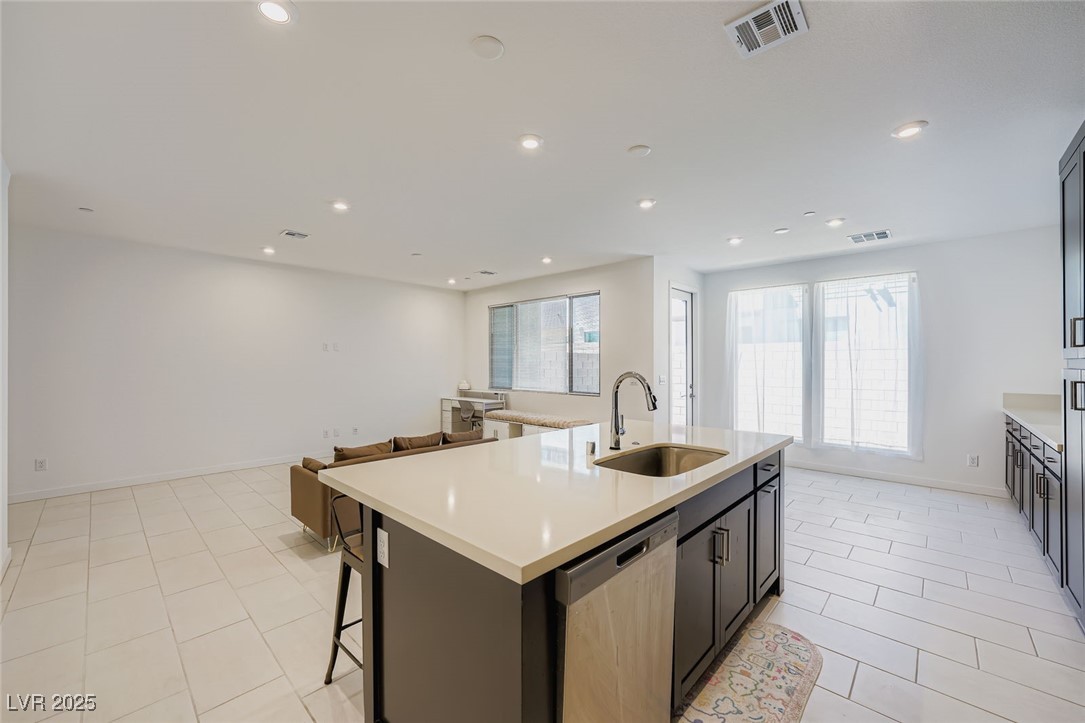 Open-plan kitchen with a large white island, dark cabinets, and a small brown sofa.