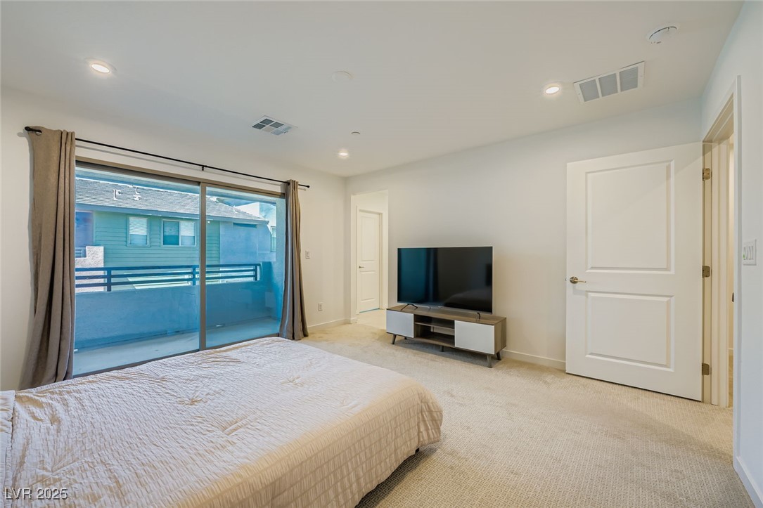 Bedroom with a bed, television, and sliding glass doors to a balcony.