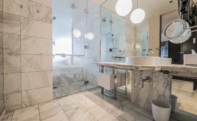 Marble bathroom with a glass shower and vessel sink.