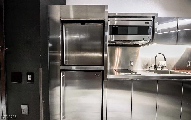 Modern kitchen with stainless-steel cabinetry, built-in appliances, and a sink.