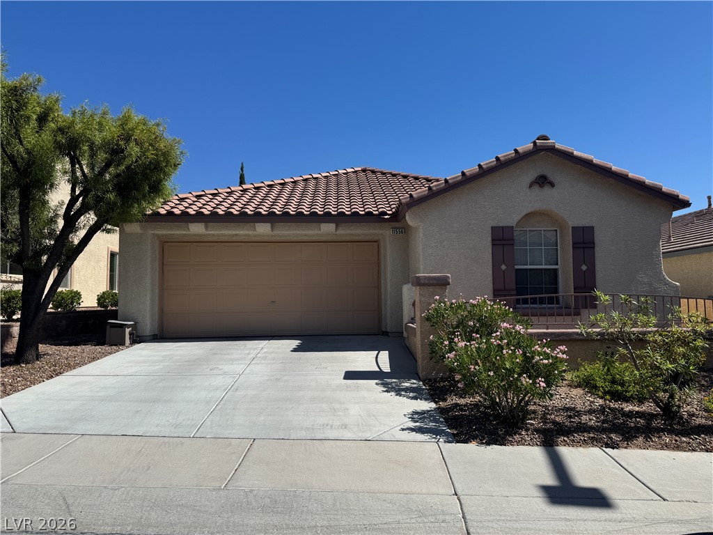 Single-story stucco home with a red tile roof, two-car garage, and landscaped front yard.