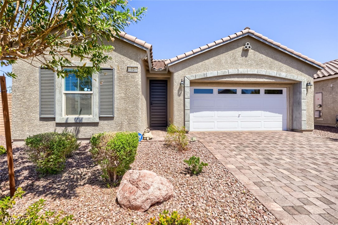 Single-story stucco home with a white double garage and desert landscaping.
