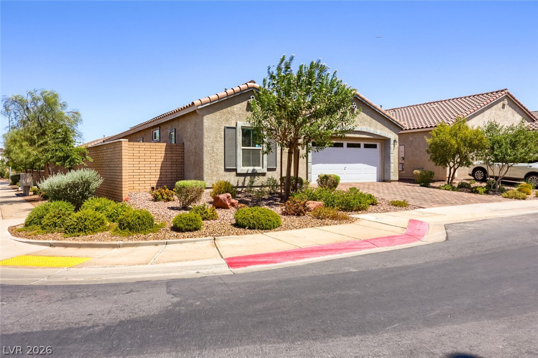 Single-story stucco home with a tile roof, white garage door, and desert landscaping.