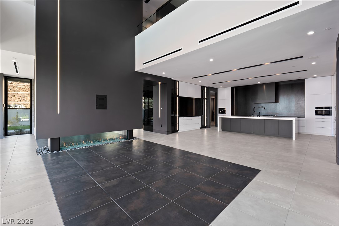Modern open-plan kitchen with a large gray island, white cabinetry, and a linear fireplace.