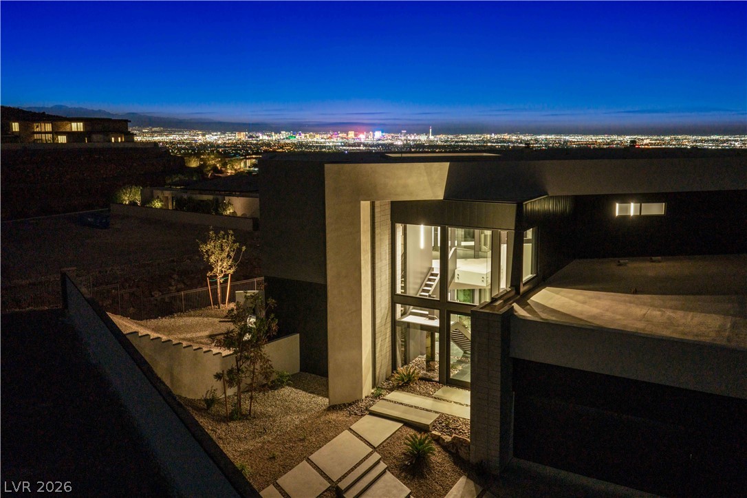 Modern Henderson home with an illuminated glass entrance and Las Vegas lights across the horizon.