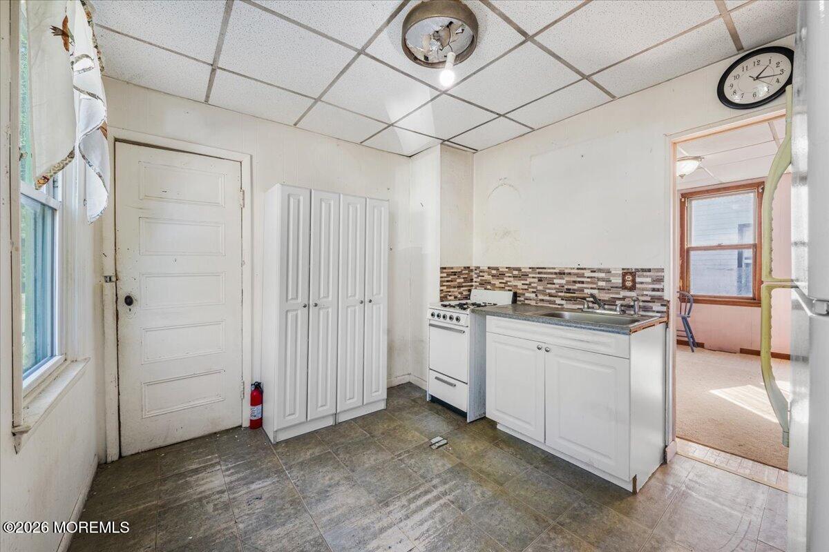 Kitchen with white cabinets, a freestanding stove, and a patterned tile backsplash.