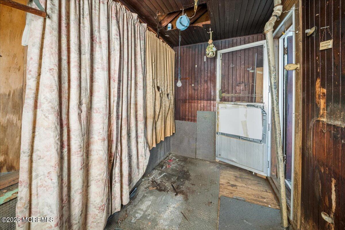 Enclosed porch with floral curtains, dark wood paneling, and a glass door.