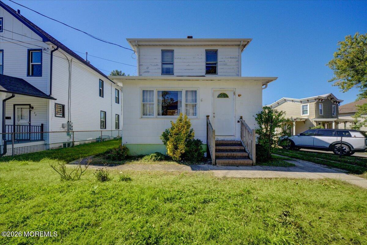 White two-story house with front steps and a broad grassy lawn.