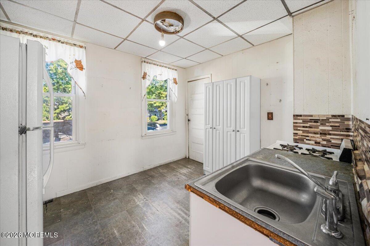 Kitchen with a stainless-steel sink, white cabinets, gas cooktop, and two windows.
