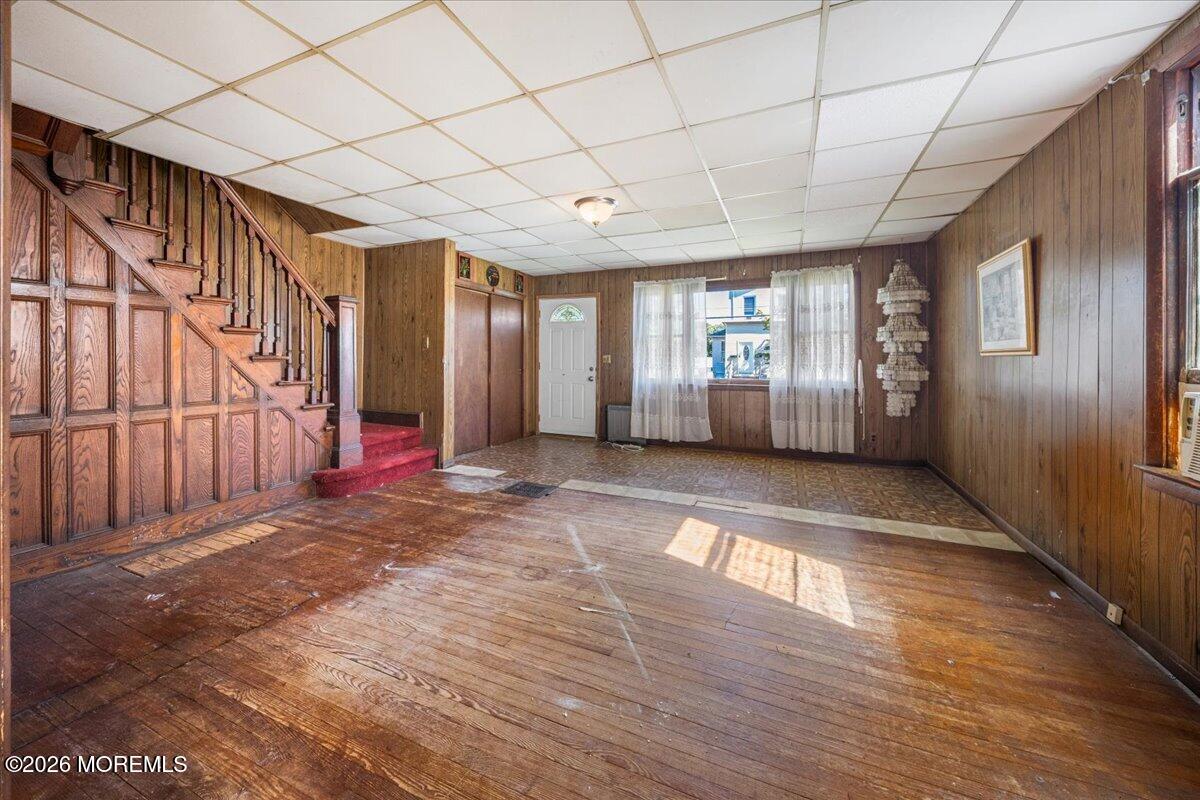 Vacant wood-paneled entry room with a broad staircase and red-carpeted steps.