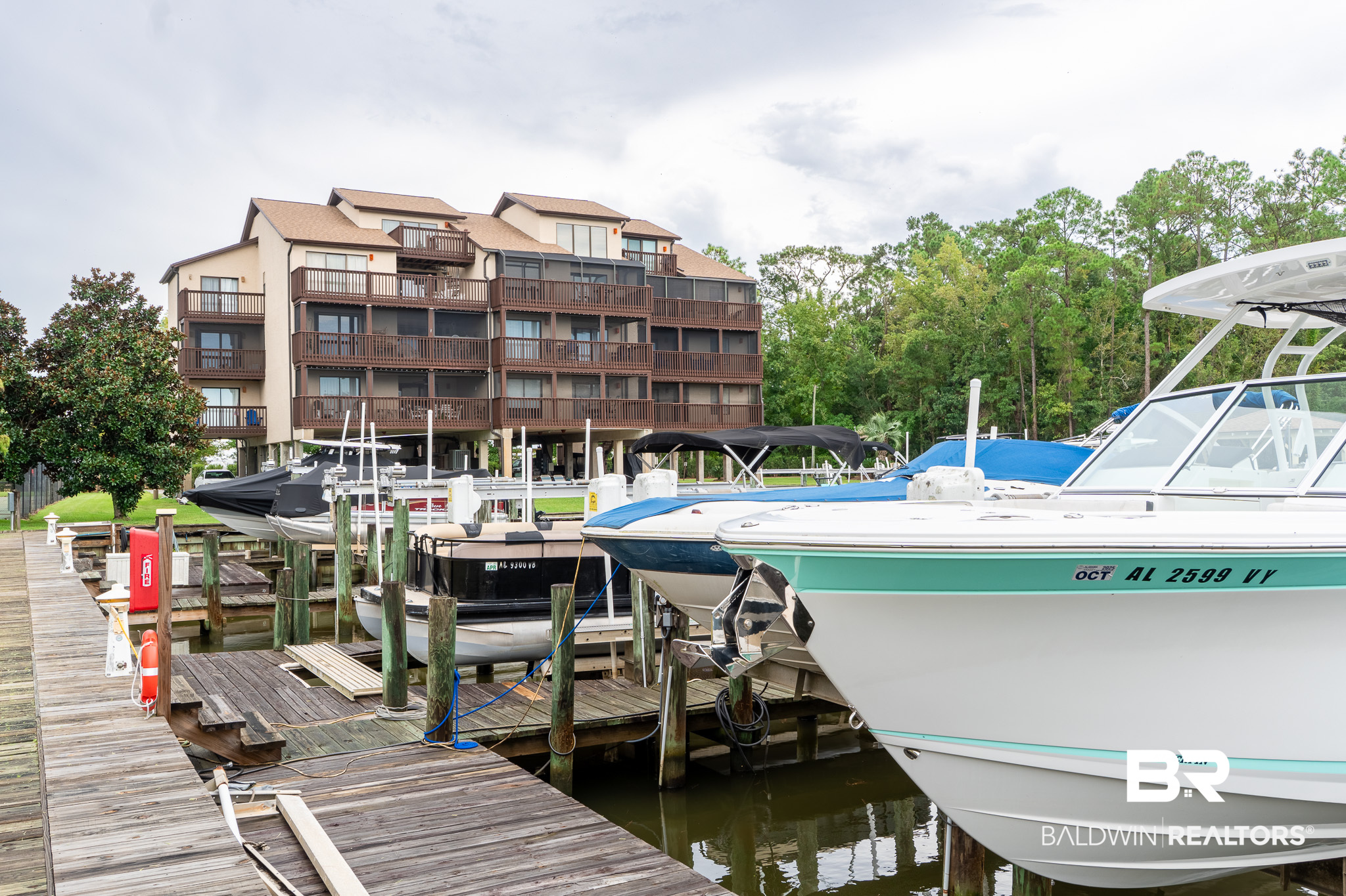 Condominium building overlooking a marina, with boats moored along wooden docks.