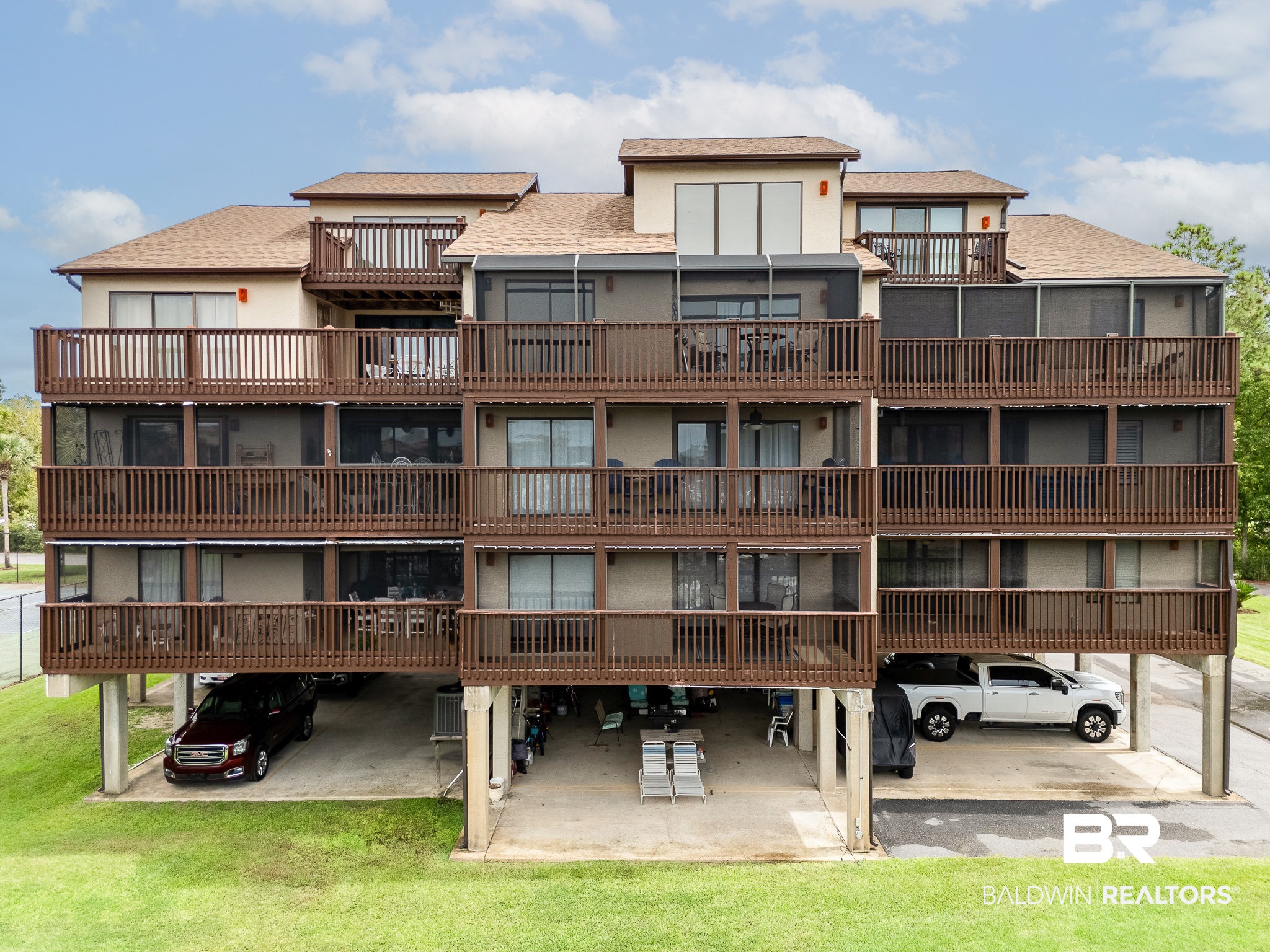 Multi-story condominium building with brown-railed balconies and covered parking below.