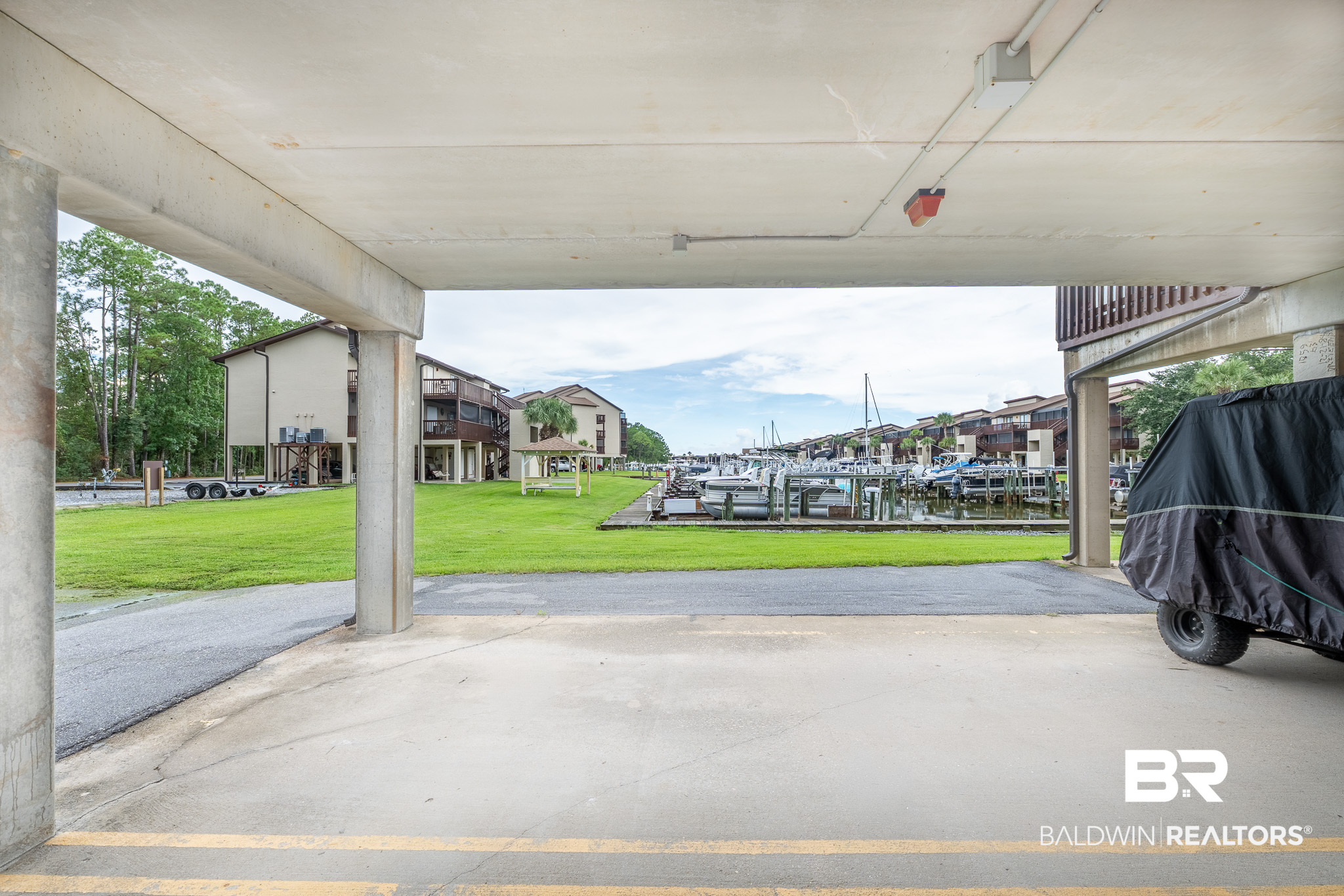 Covered parking area overlooks a marina, boats, and waterfront condominium buildings.