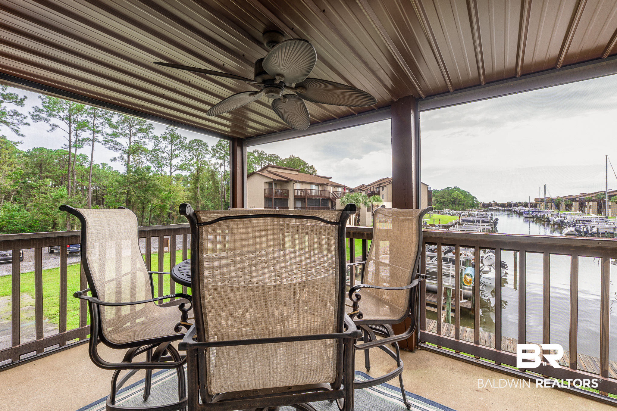Covered balcony with outdoor seating overlooking a marina and docked boats.