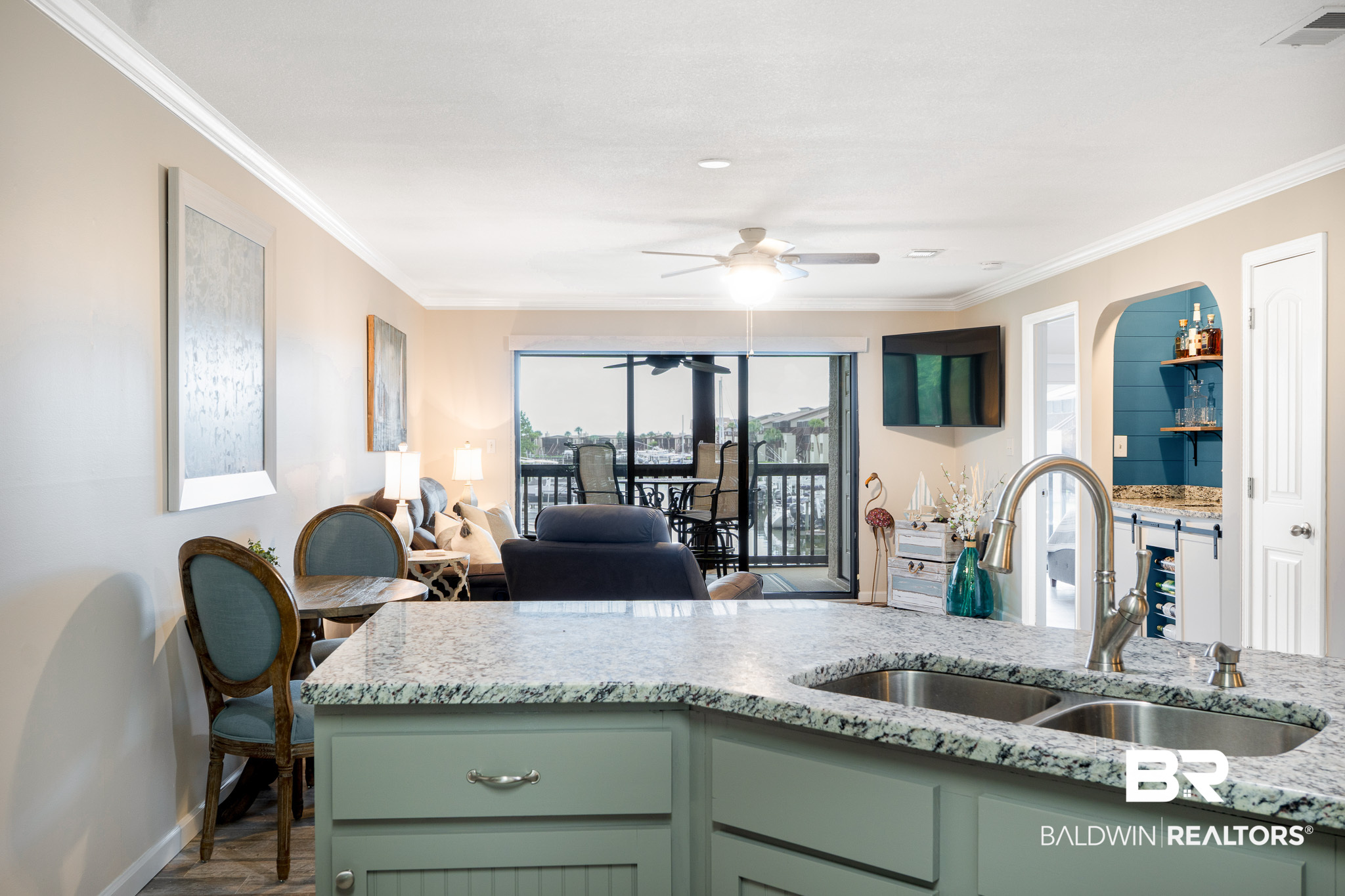Open-plan kitchen and living area with a granite island and marina views through sliding glass doors.