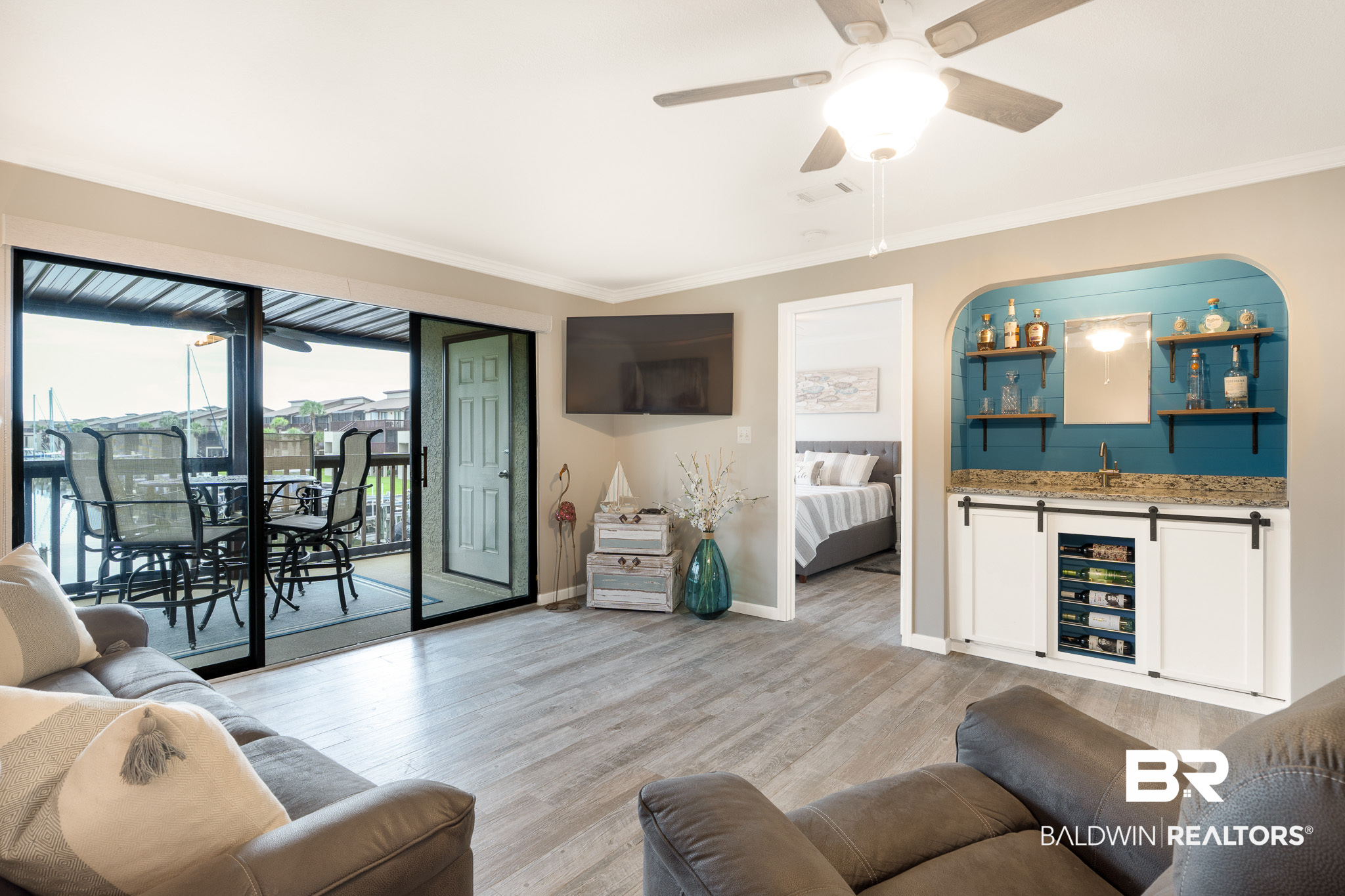 Living room with a teal-backed built-in bar and sliding doors to a water-view balcony.