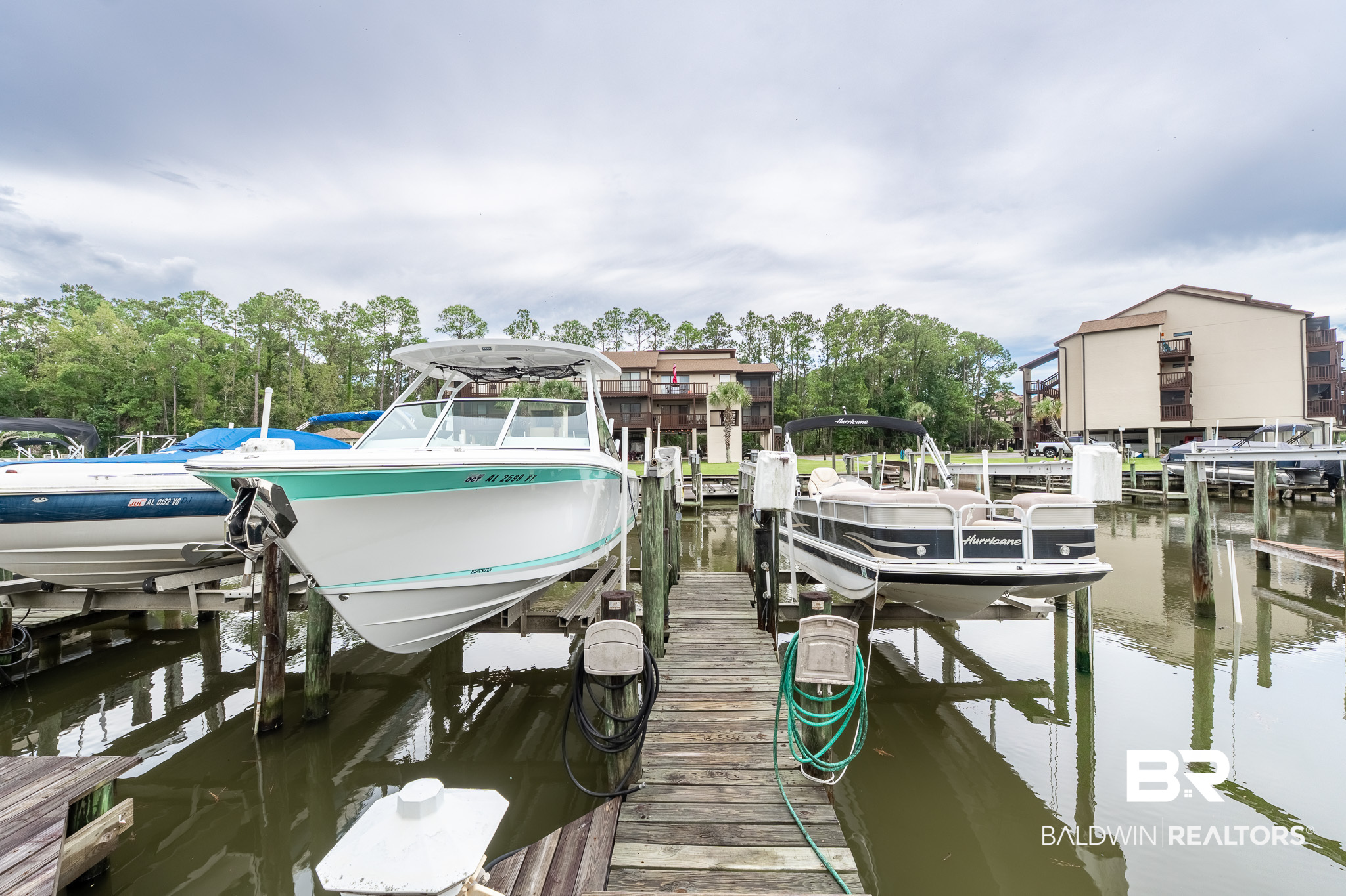 Marina dock with several boats in front of waterfront condominiums.