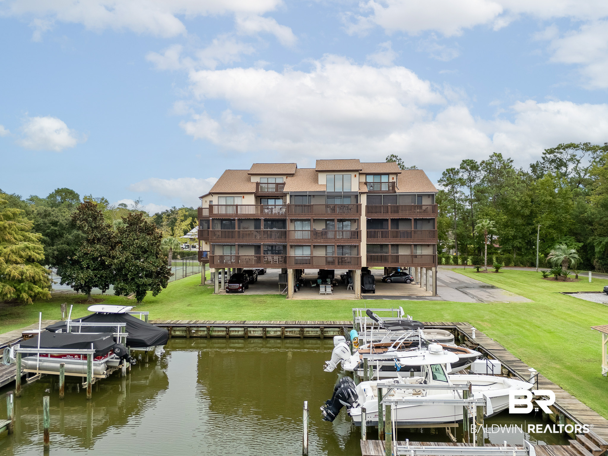 Condominium building beside a marina, with boats docked in the foreground and balconies facing the water.