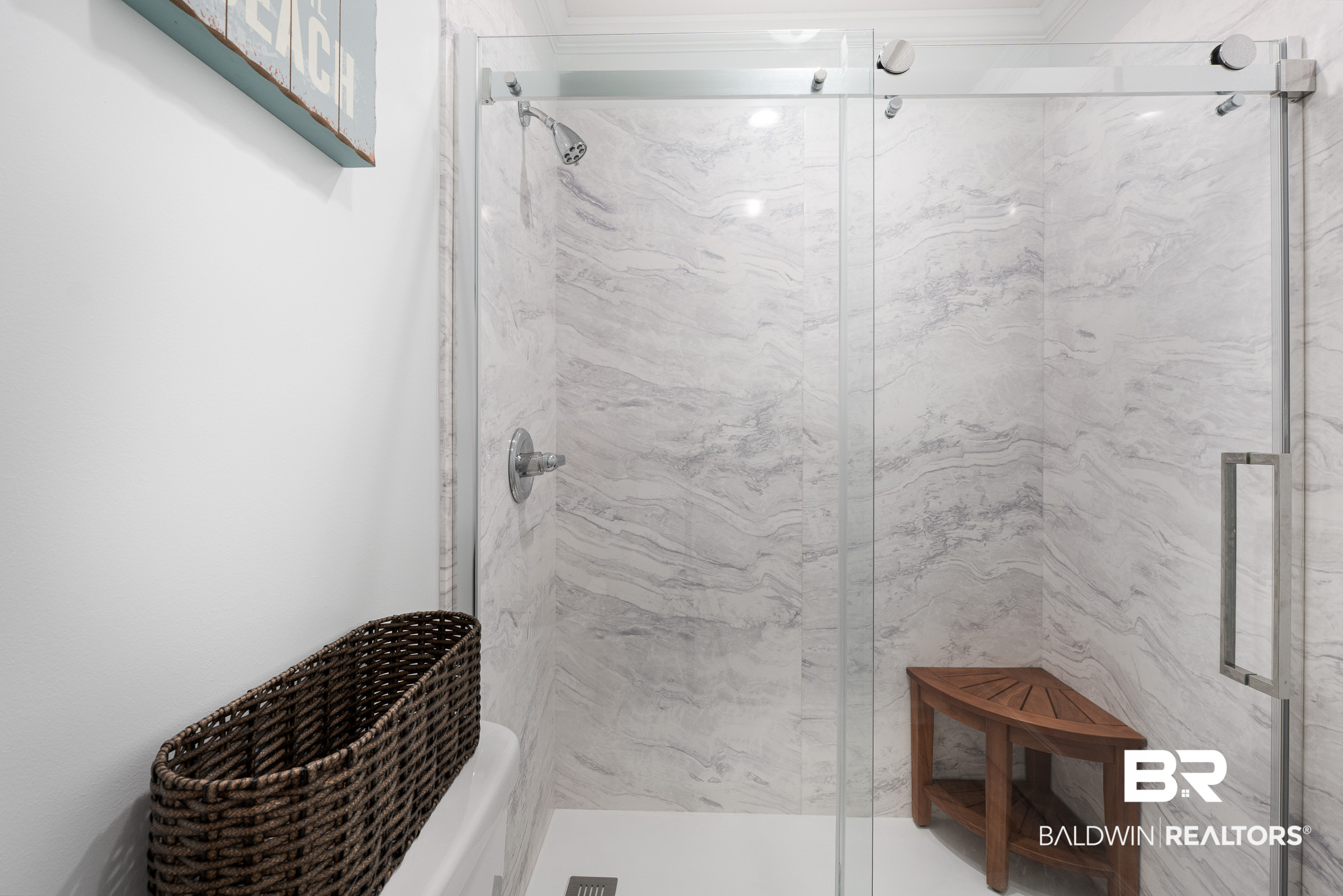 Marble-tiled walk-in shower with glass doors and a wooden corner bench.