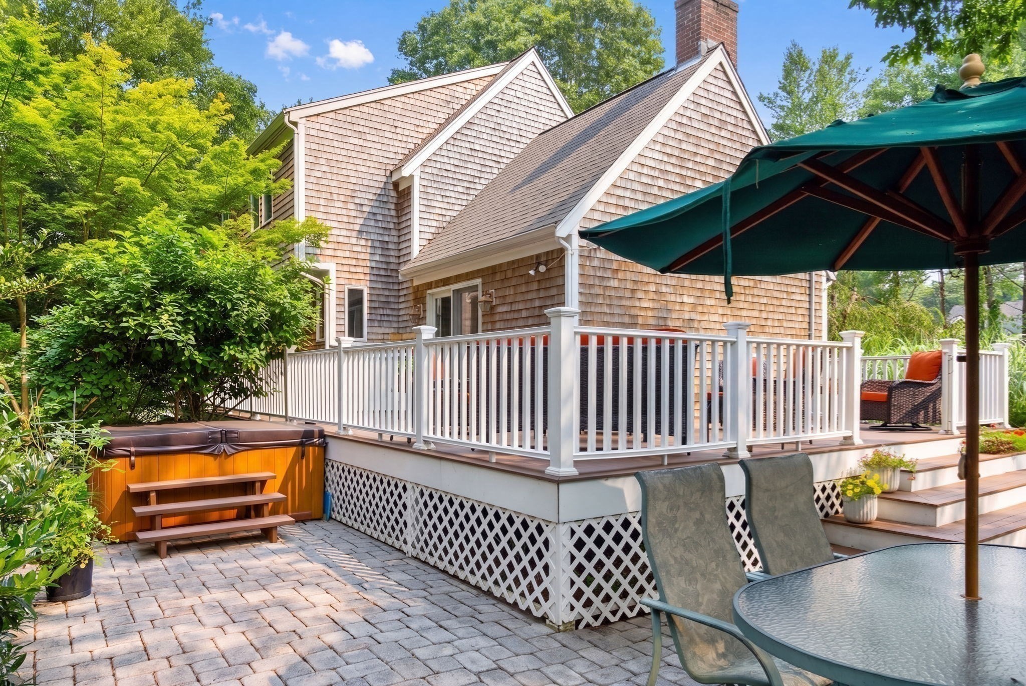 Shingle-sided home with a raised deck, hot tub, and furnished patio.