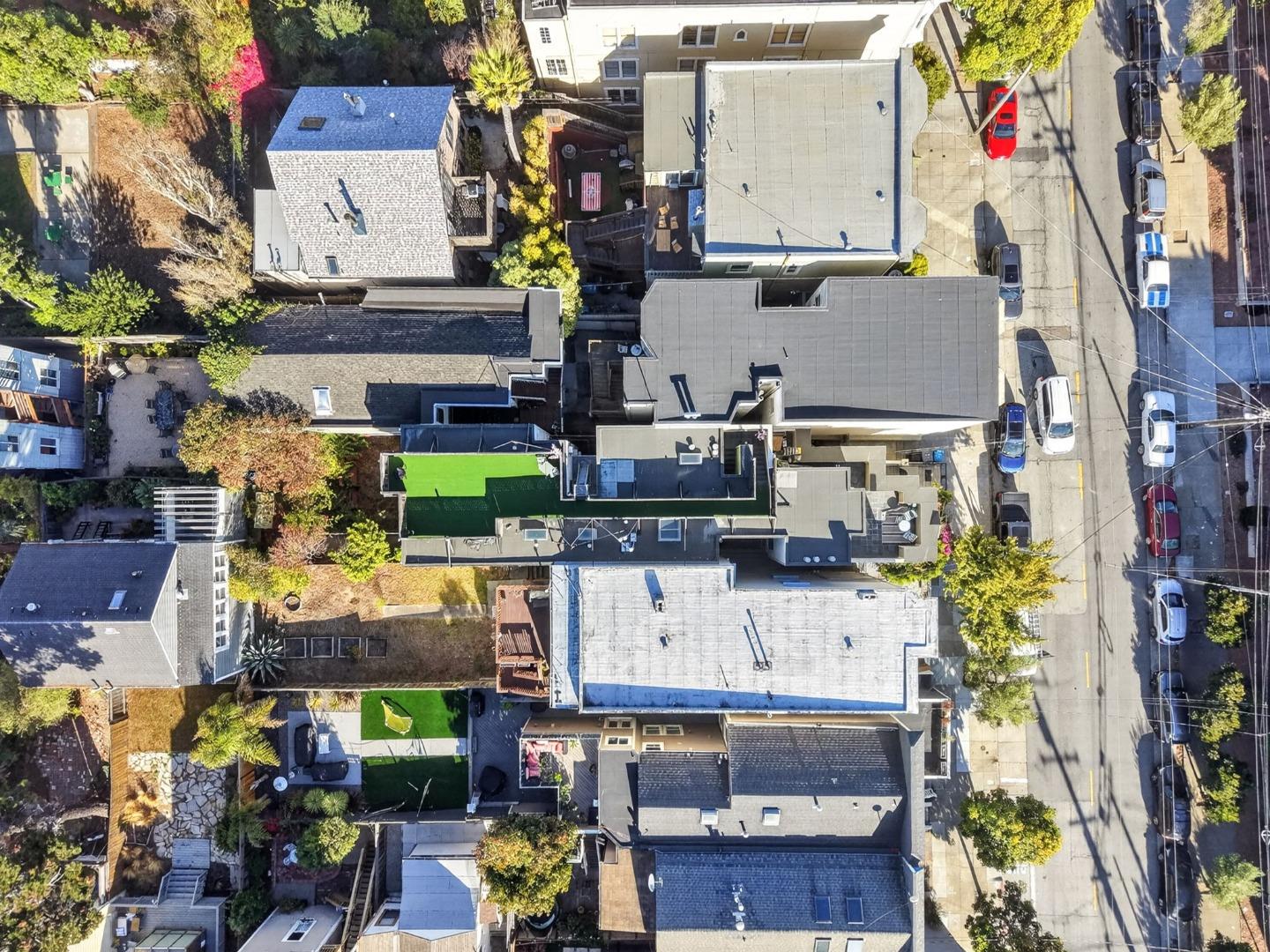 Aerial view of a San Francisco residential block with flat rooftops, landscaped yards, and parked cars.