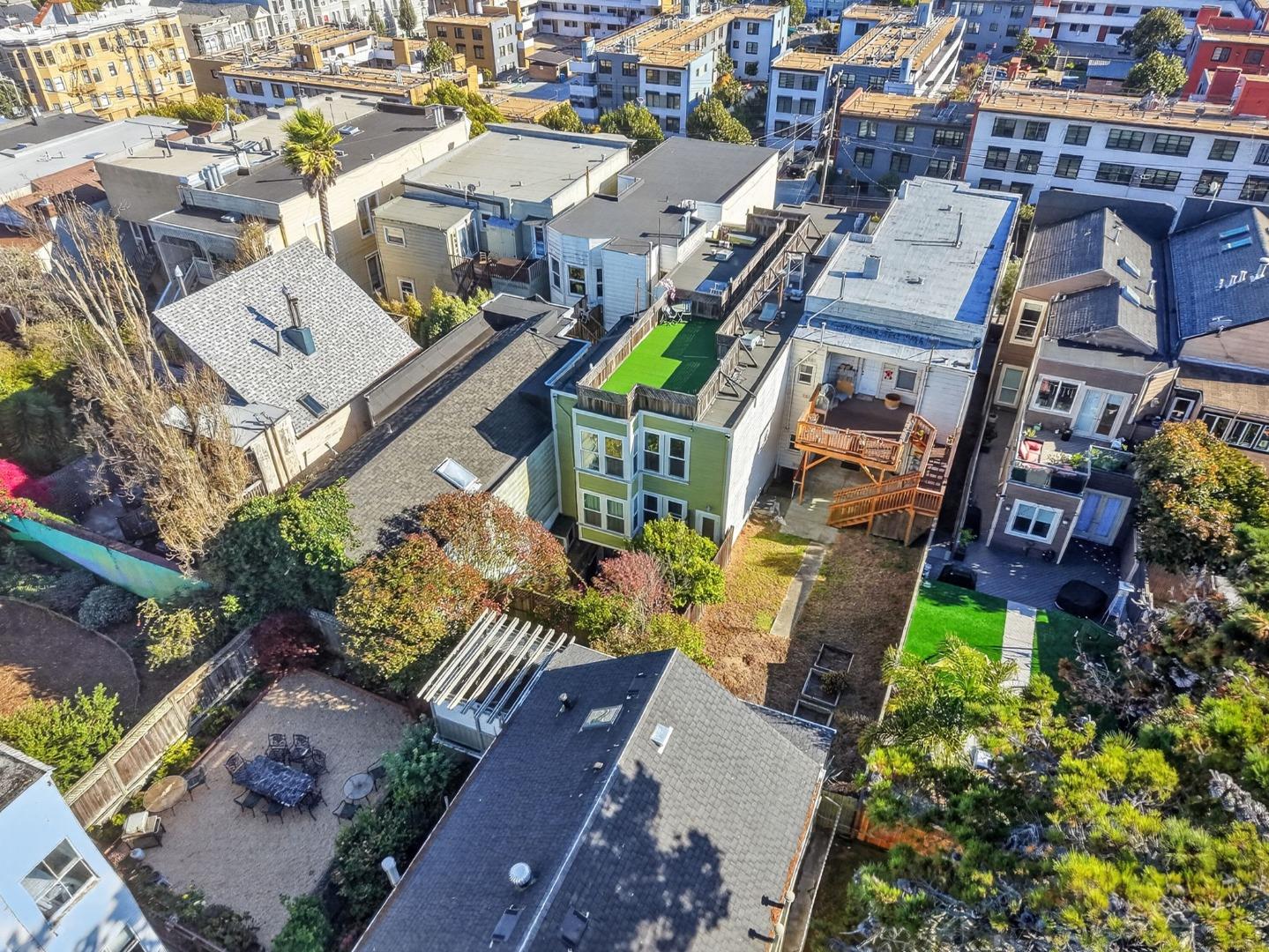 Aerial view of a green San Francisco home with a bright turf rooftop deck among neighboring houses.
