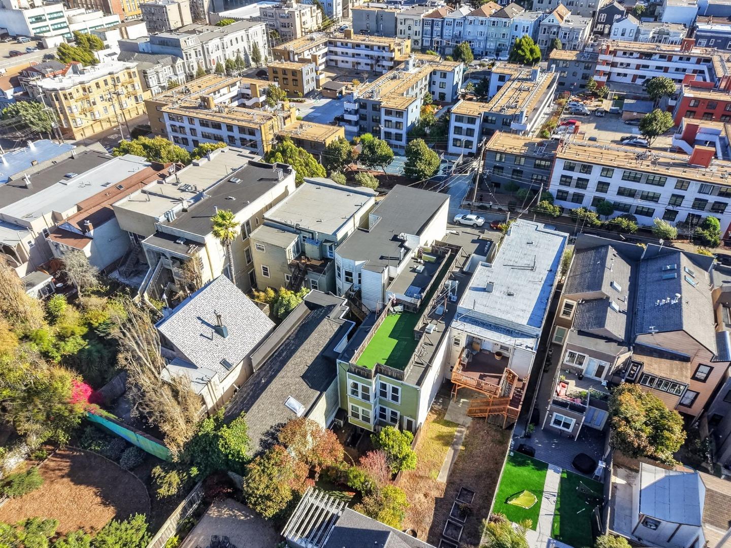 Aerial view of dense San Francisco homes and rooftops, with a green-turfed backyard.