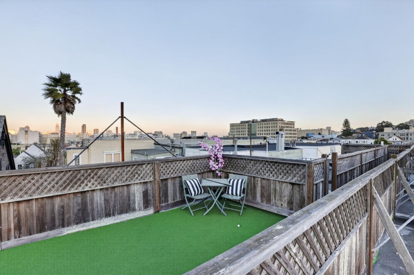Rooftop deck with green turf and seating overlooking San Francisco rooftops and skyline.