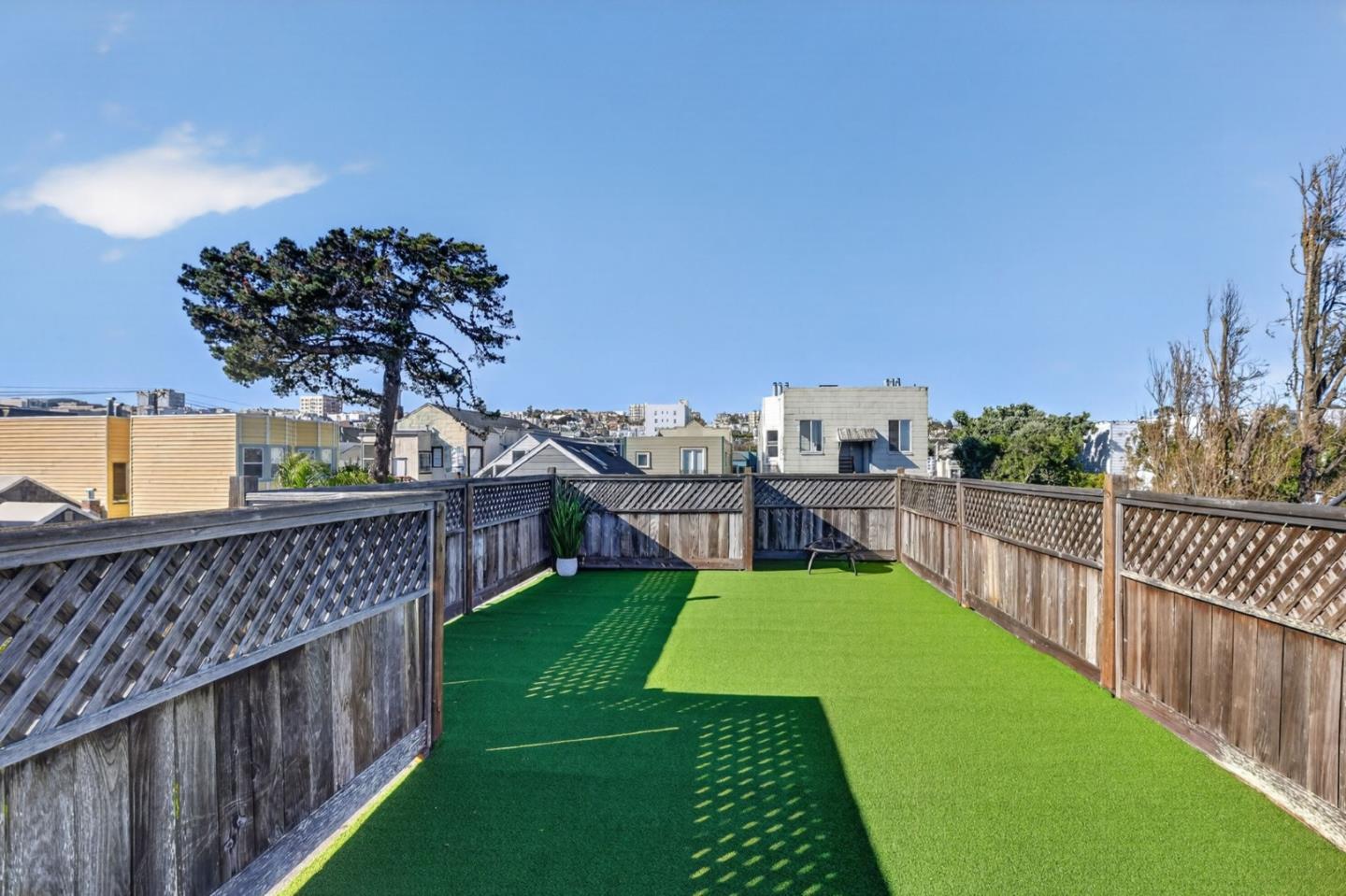 Rooftop terrace with artificial turf, lattice fencing, and views over nearby rooftops.