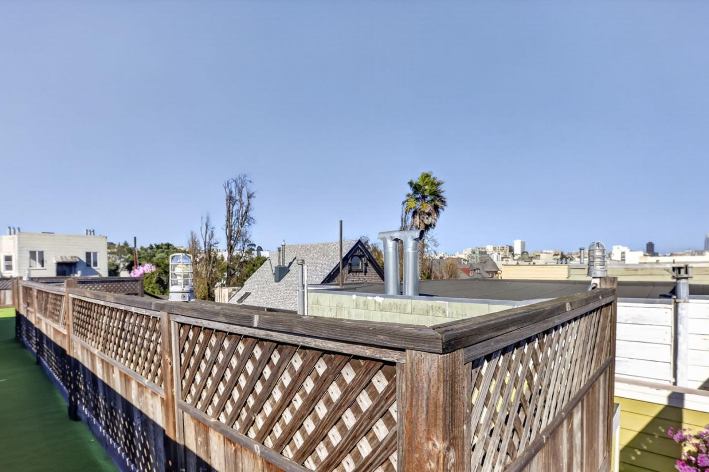 Rooftop deck with a wooden lattice railing and views of nearby city rooftops.
