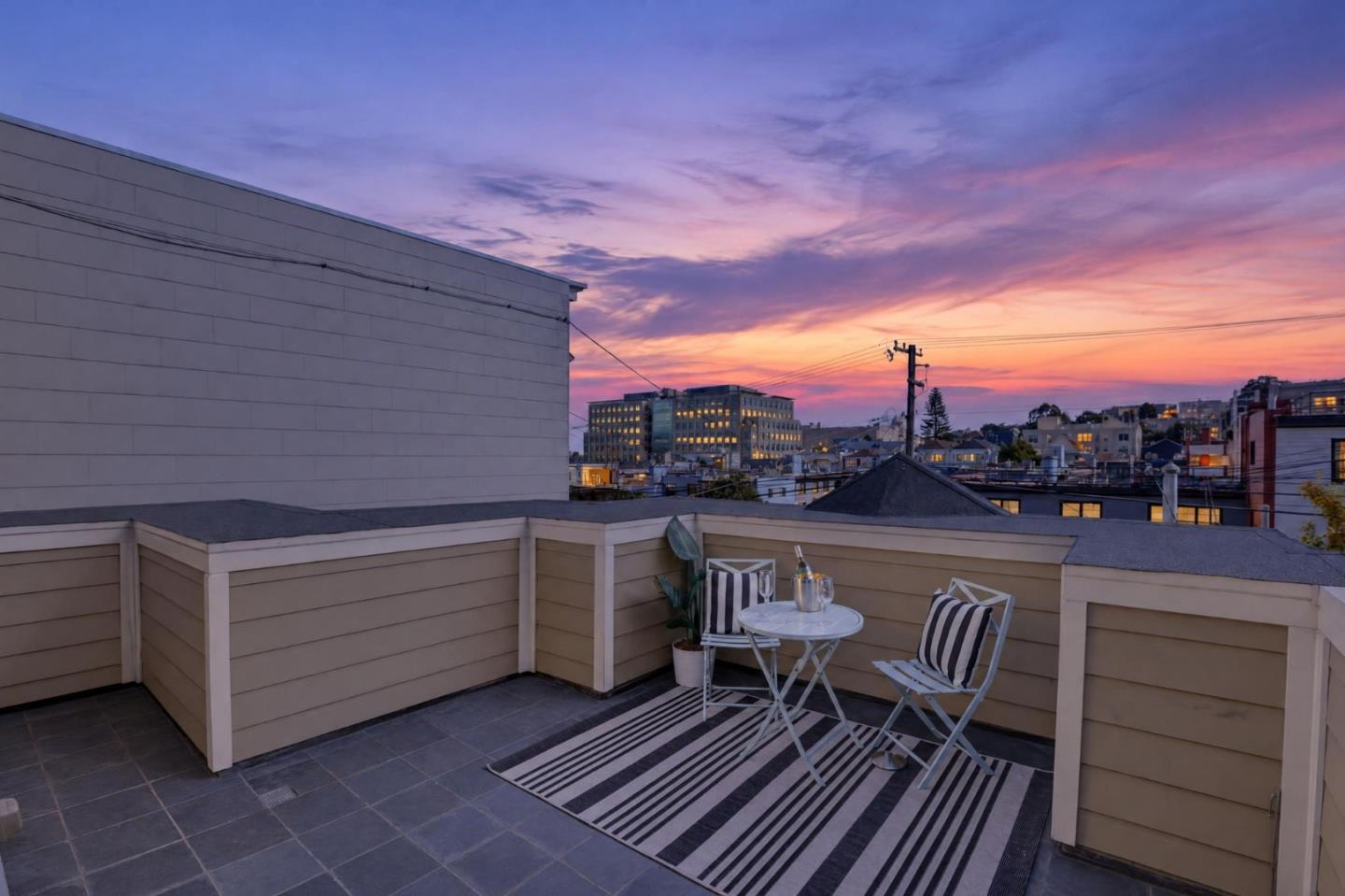 Rooftop terrace with striped outdoor seating overlooking the city at dusk.
