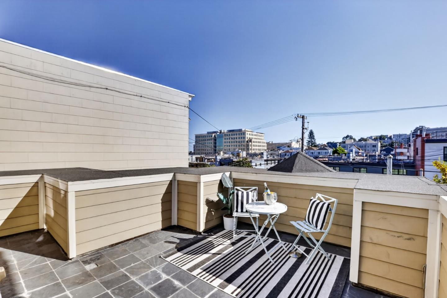 Rooftop terrace with striped seating, a tiled floor, and views of surrounding city buildings.