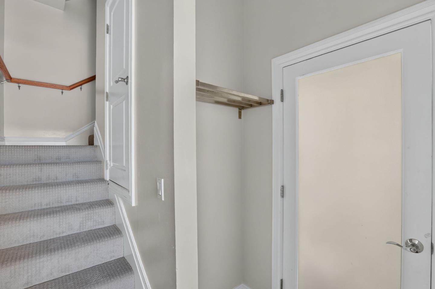 Hallway with carpeted stairs, a wooden handrail, and a white door.