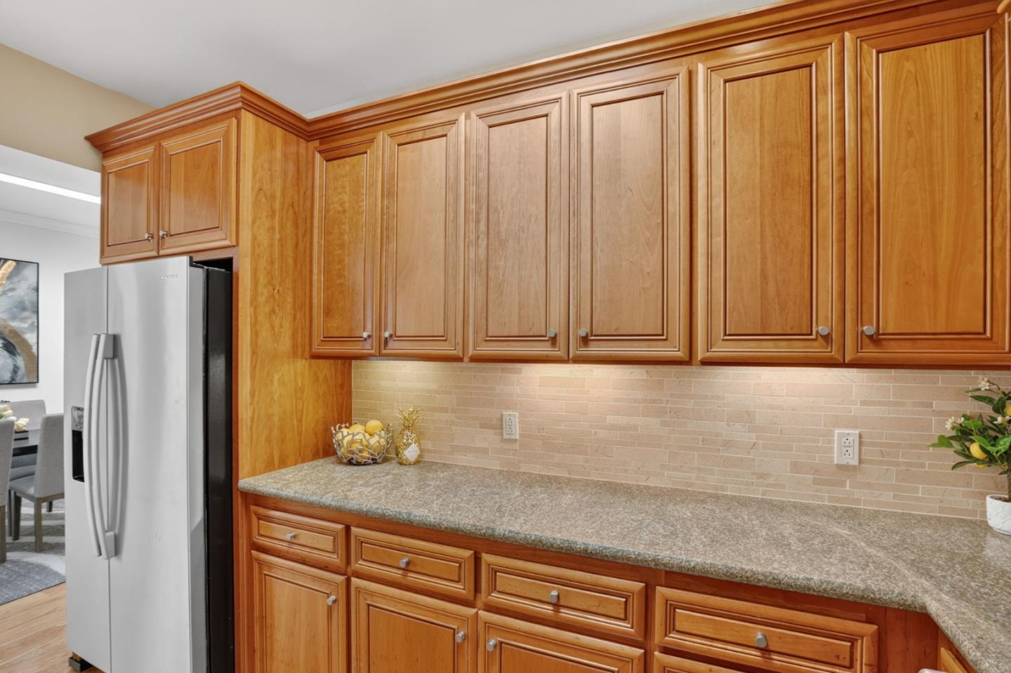 Kitchen with warm wood cabinets, a stone countertop, and a stainless steel refrigerator.