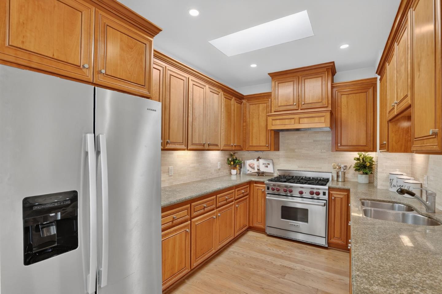 Kitchen with honey-colored wood cabinets, granite counters, stainless steel appliances, and a double-basin sink.