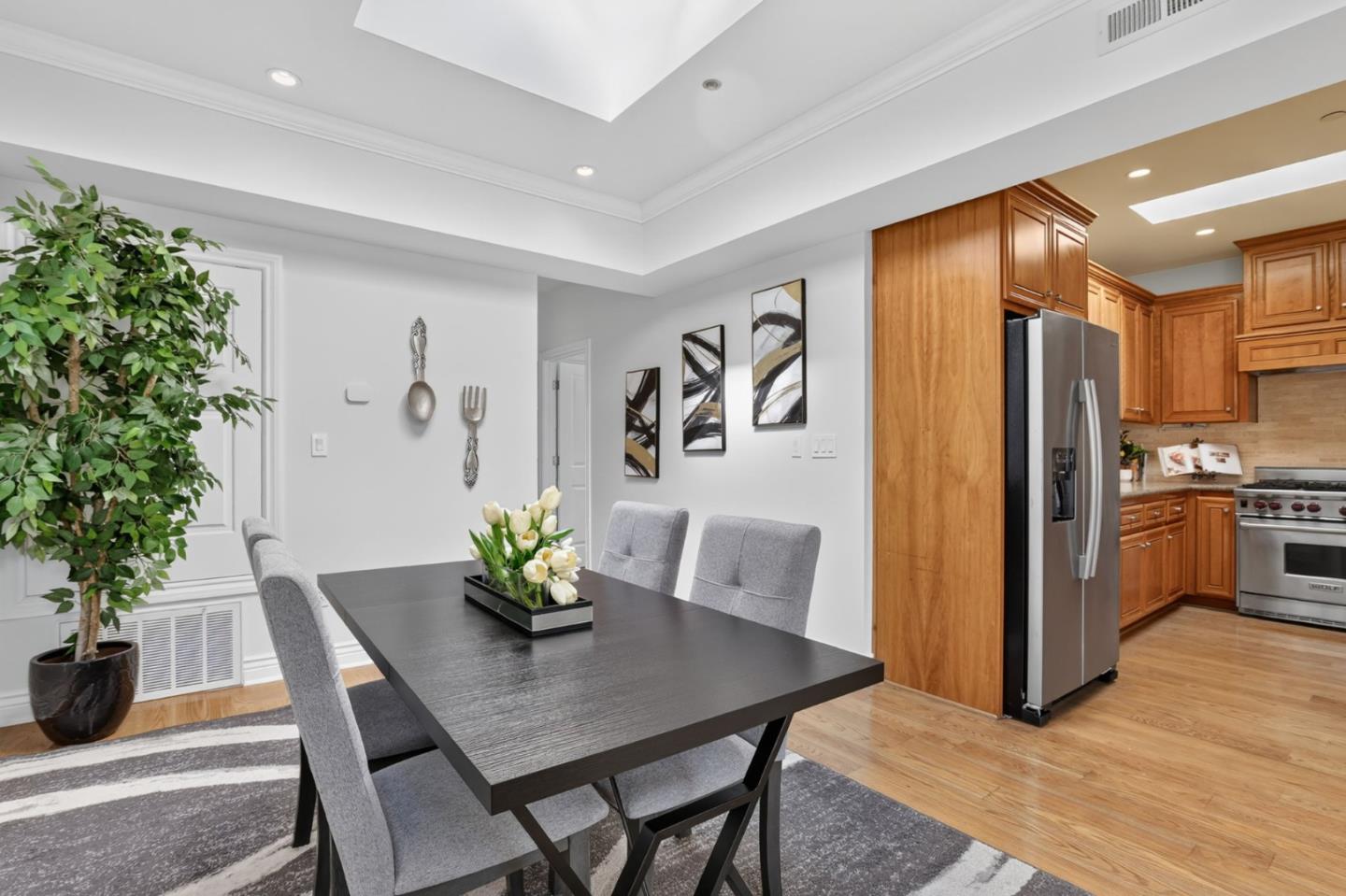 Dining area with a dark table and gray chairs opening into a wood-cabinet kitchen.