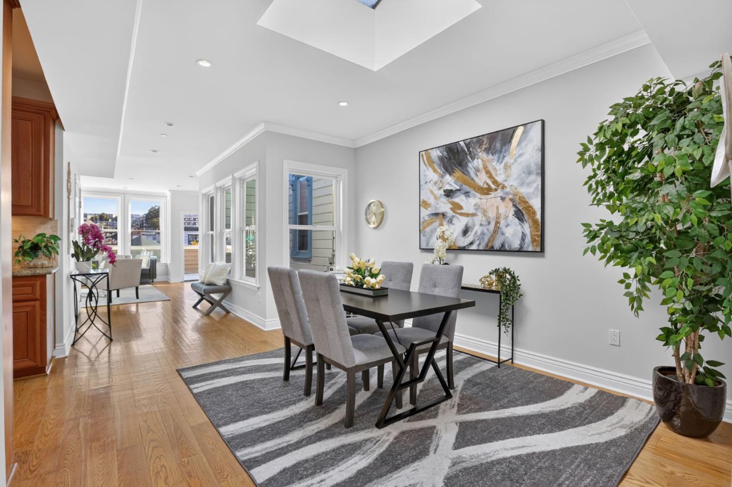 Dining room with a dark table, gray chairs, patterned rug, and tall windows.