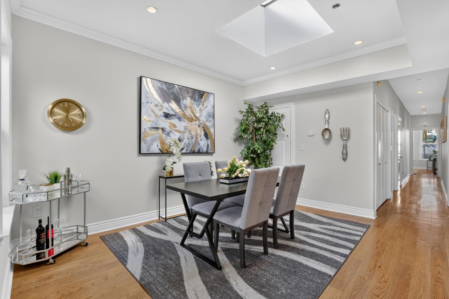 Dining room with a black table, gray chairs, striped rug, and abstract wall art.