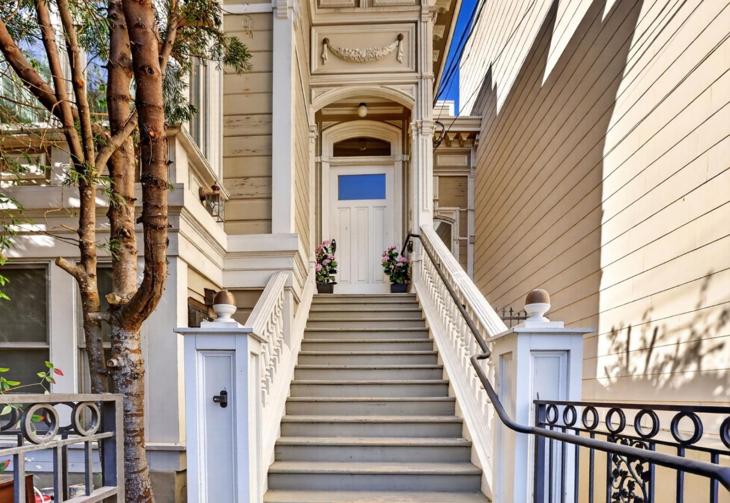 Front entrance of 2568 Sutter Street, with broad stairs, ornate trim, and potted flowers.