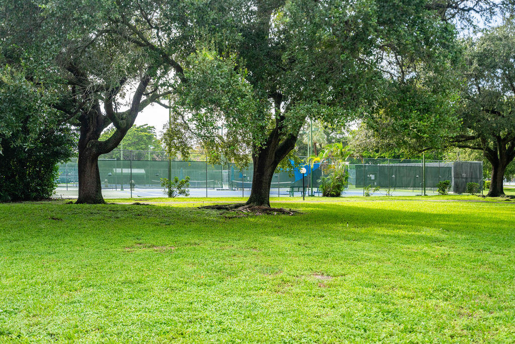 Fenced tennis courts behind a broad, tree-shaded lawn.
