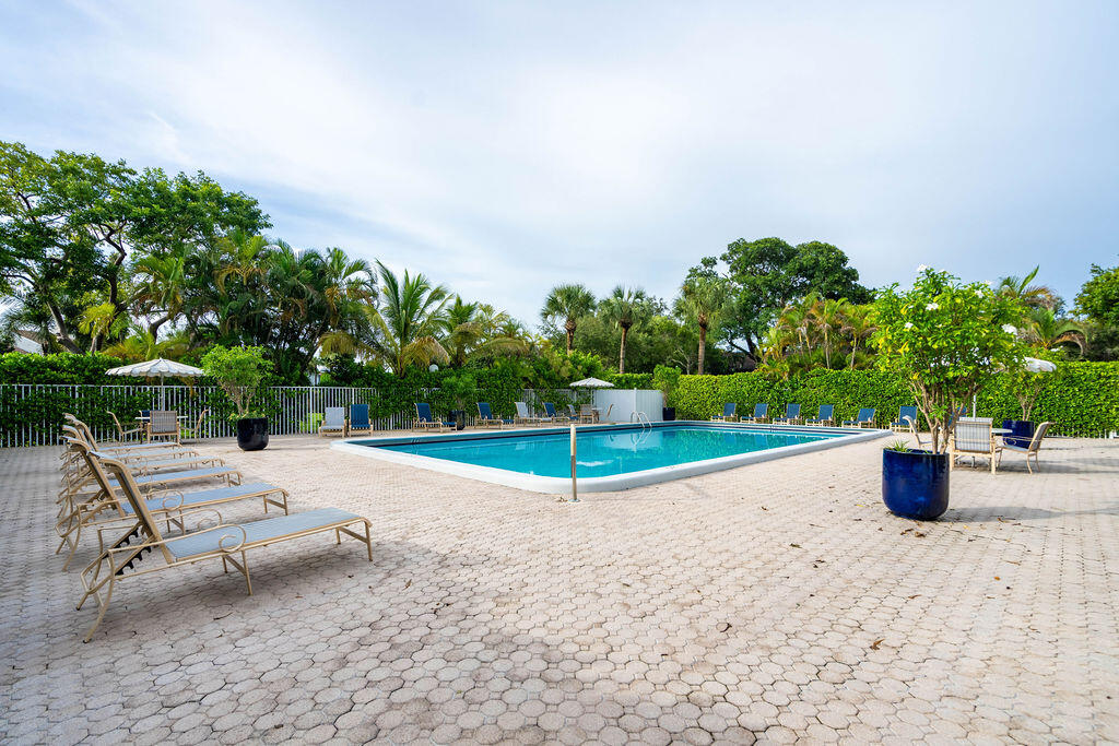 Outdoor swimming pool with paved deck, lounge chairs, and tropical landscaping.