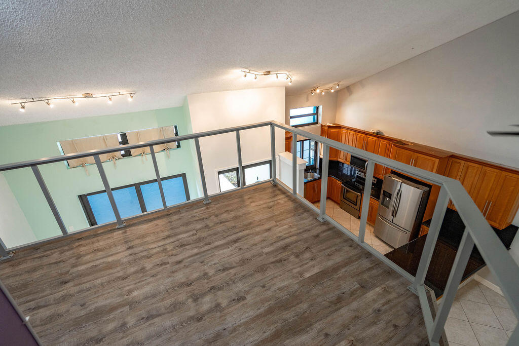 Open loft overlooking a kitchen with wood cabinets and stainless steel appliances.