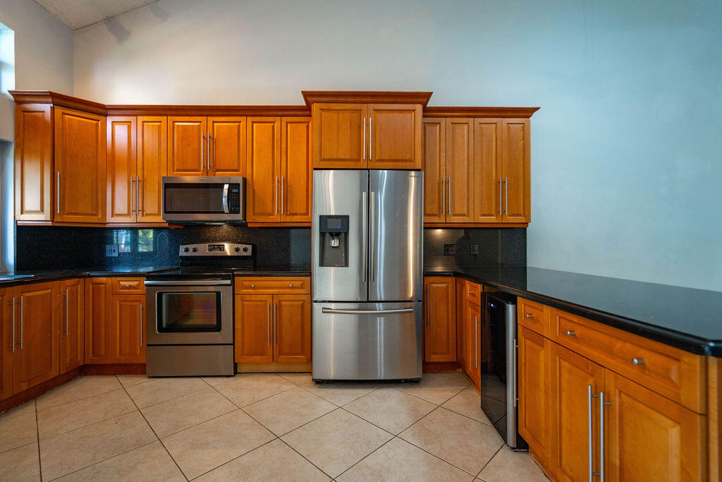 Kitchen with wood cabinetry, black countertops, and stainless steel appliances.