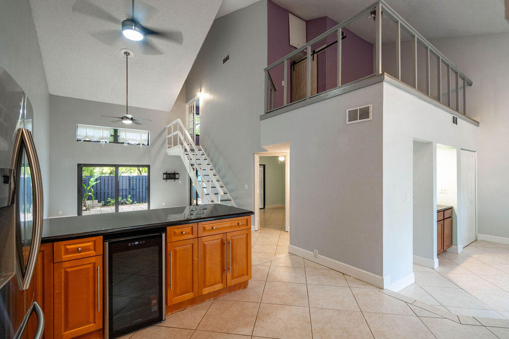 Open-plan kitchen with honey-toned cabinets, tiled floors, and a staircase to an open loft.
